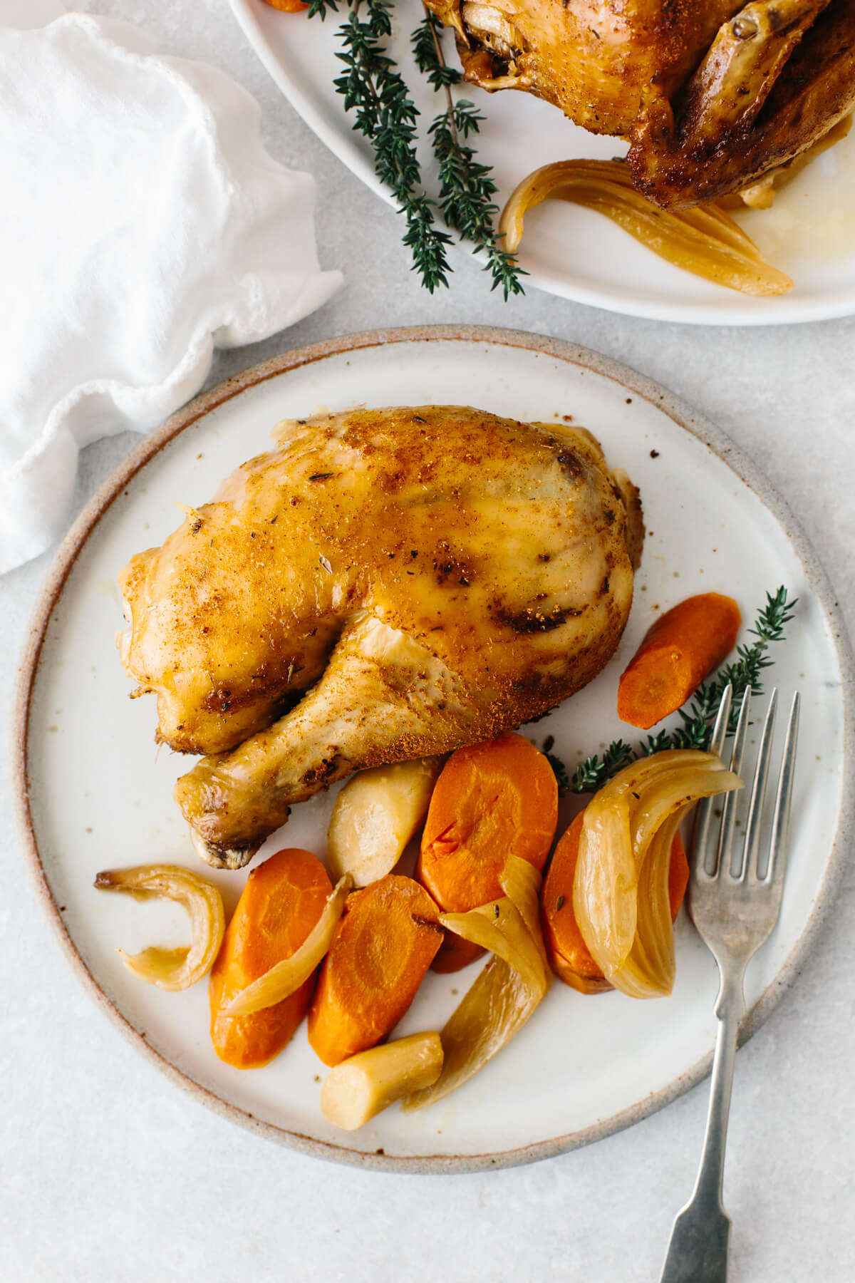 A chicken thigh and vegetables on a plate.