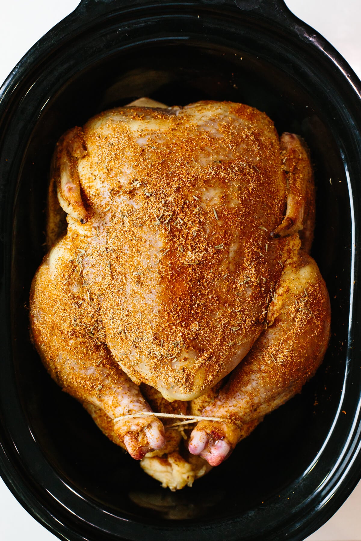 Chicken rubbed with herbs in slow cooker.