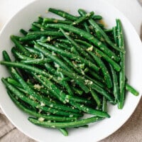 Green beans topped with lemon in a white bowl.