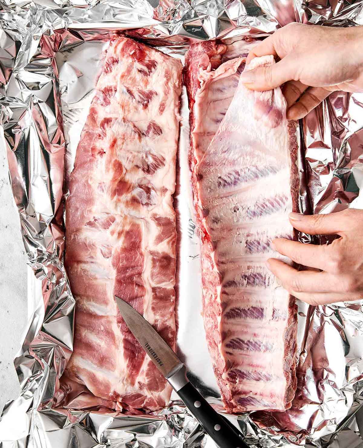 These baby back ribs are my secret to the best cookout meal. Guaranteed to be fall-apart tender with the best pineapple BBQ sauce! Prepping baby back ribs on a sheet pan.