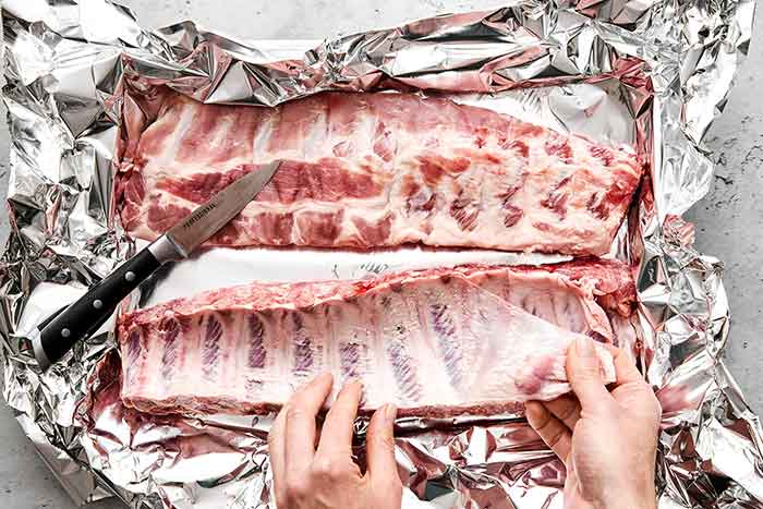 Prepping baby back ribs on a sheet pan.