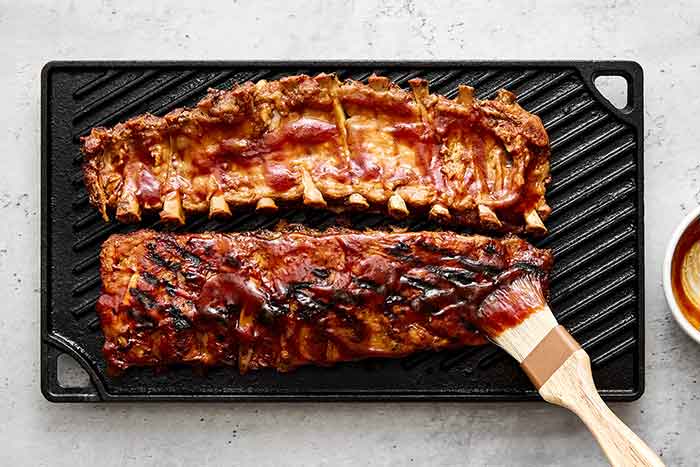 Finishing baby back ribs on a grill.