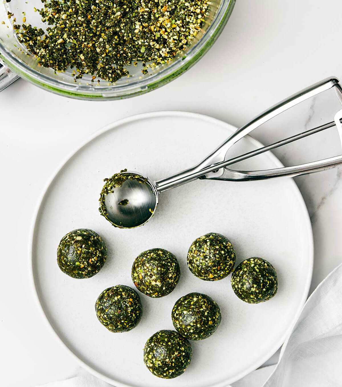 These matcha pistachio energy balls are my favorite power-packed healthy snack. Plus, they’re super easy to make and prep for the week! Rolled up matcha energy balls on a plate.
