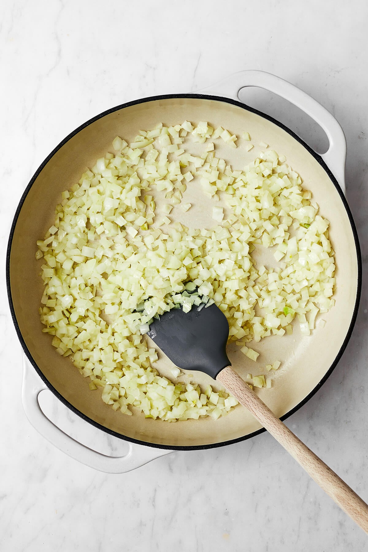 A white pan with cooked onions for pork meatballs