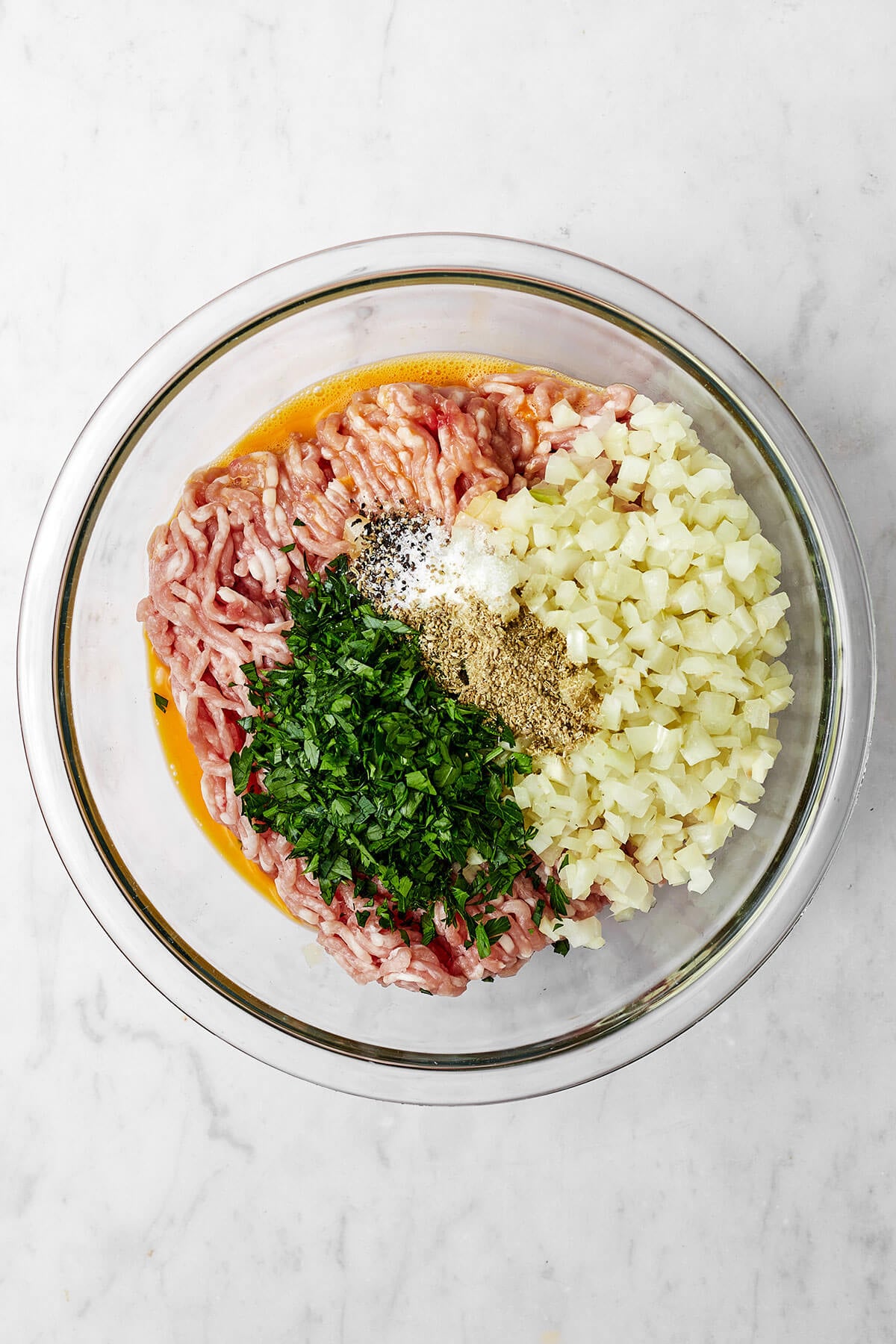 Ingredients for pork meatballs in a glass bowl