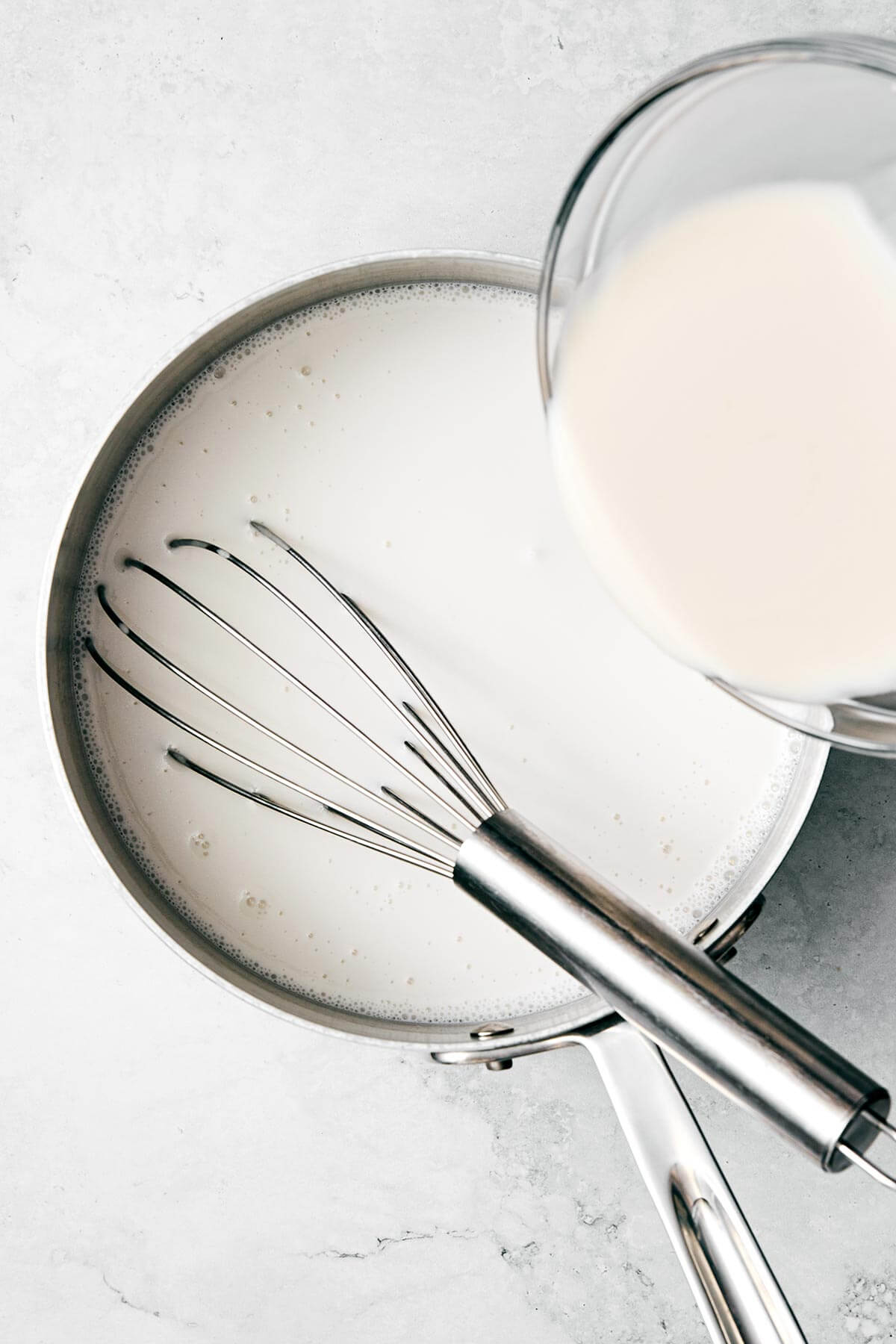 Stirring coconut yogurt in a pot.