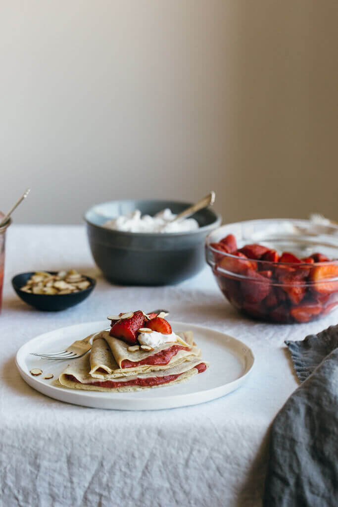 (gluten-free, paleo) Vanilla bean cassava flour crepes with strawberry chia jam. Sweet breakfast crepes are filled with homemade strawberry chia jam and topped with coconut whipped cream and almonds.