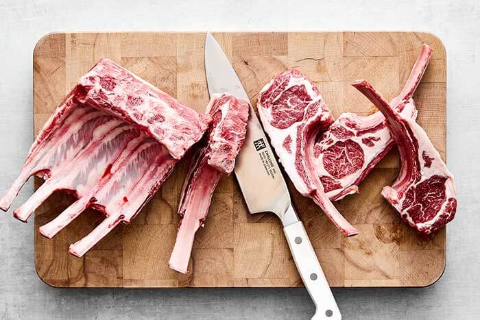 Slicing lamb chops to prepare for grilling.
