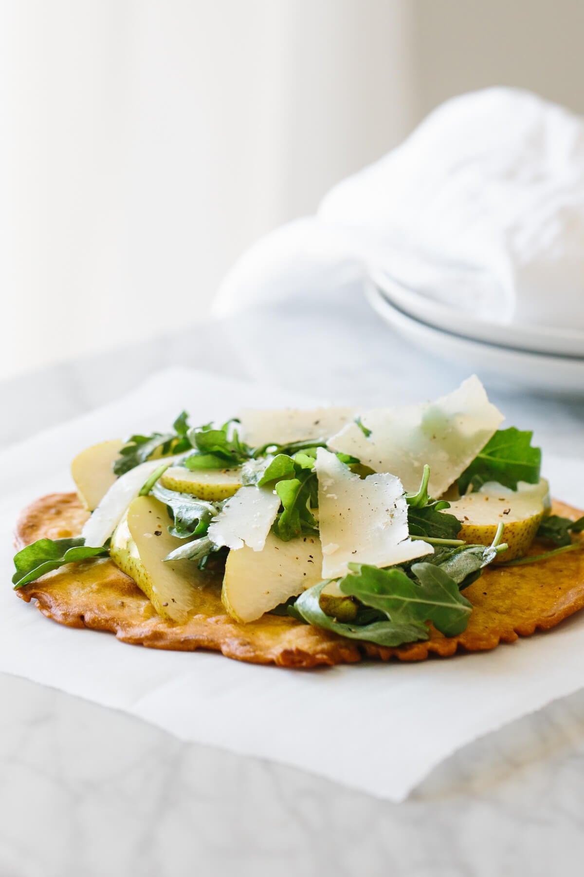 Socca is a nutty, herby chickpea flatbread that's naturally gluten-free! Socca on the counter with toppings.