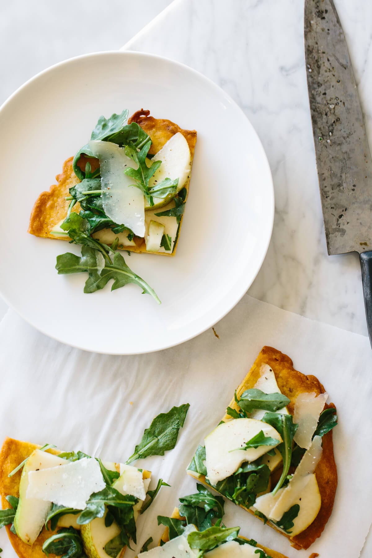 Socca is a nutty, herby chickpea flatbread that's naturally gluten-free! A slice of socca on a plate.