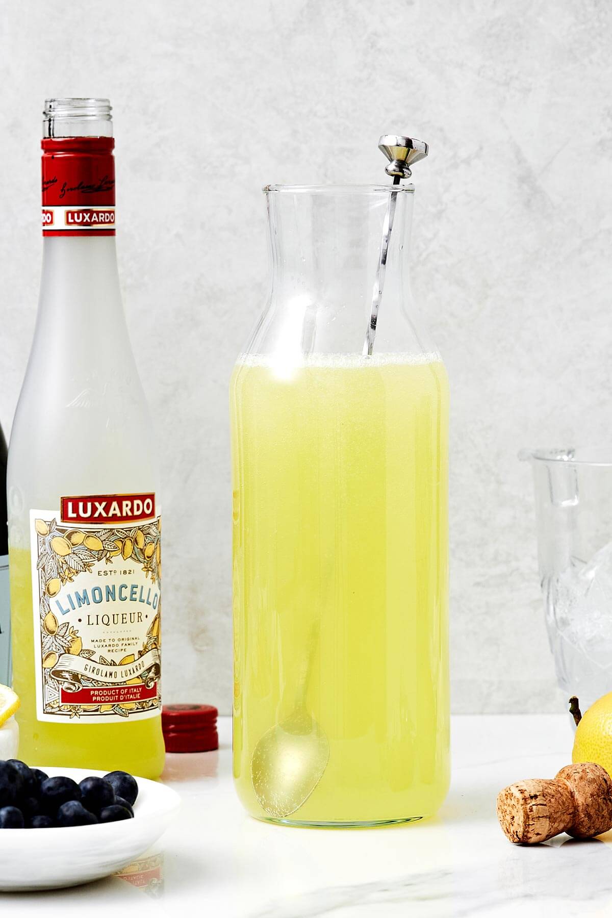 This limoncello prosecco is the summer cocktail you'll be sipping on all season long. It's got sparkling lemony goodness with fresh blueberries and thyme. Stirring limoncello prosecco in a jar.