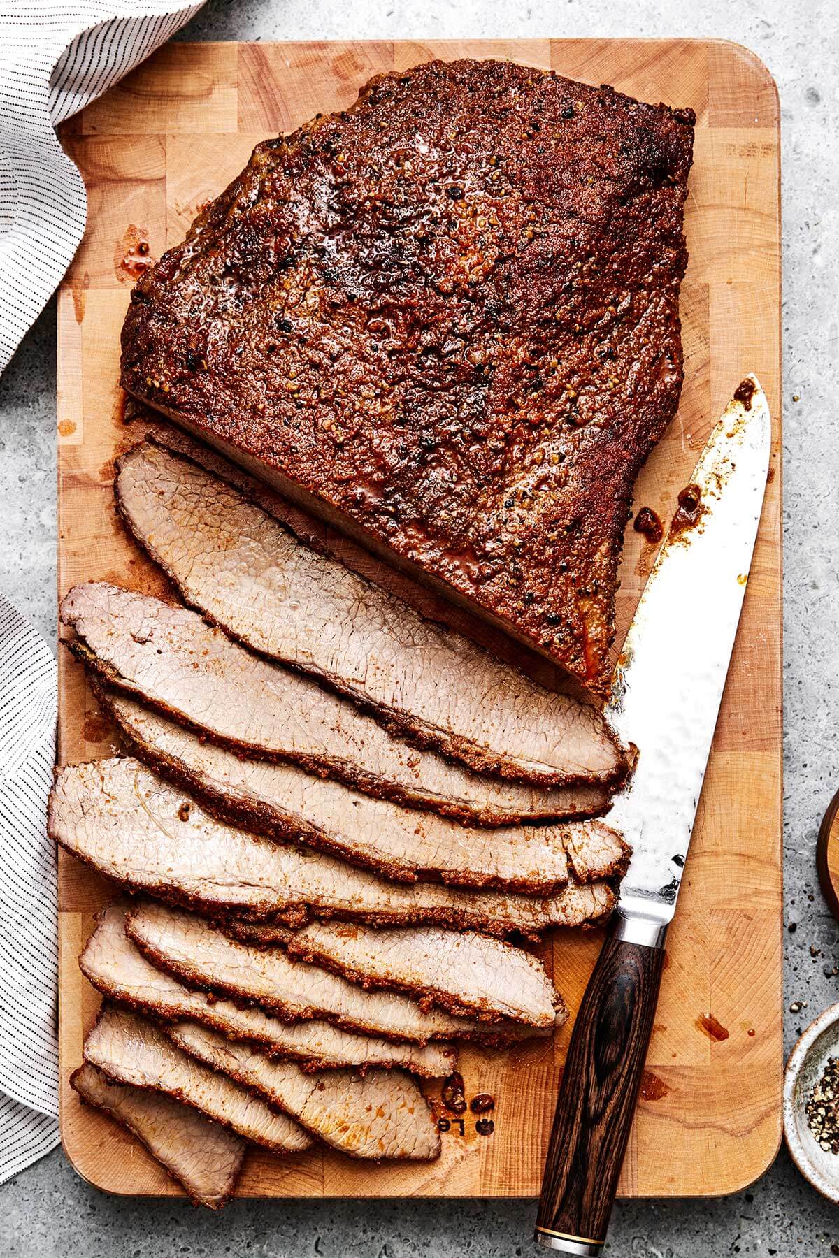 Sliced beef brisket on a wooden board.