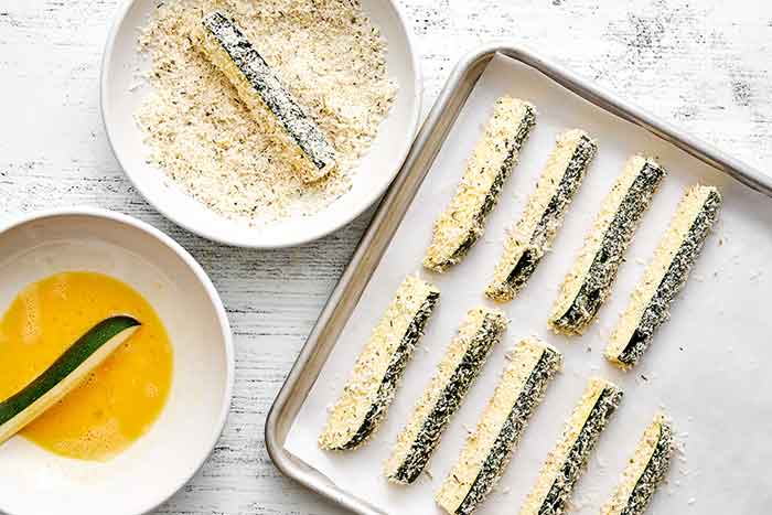 Coating zucchini fries with cheese and egg.