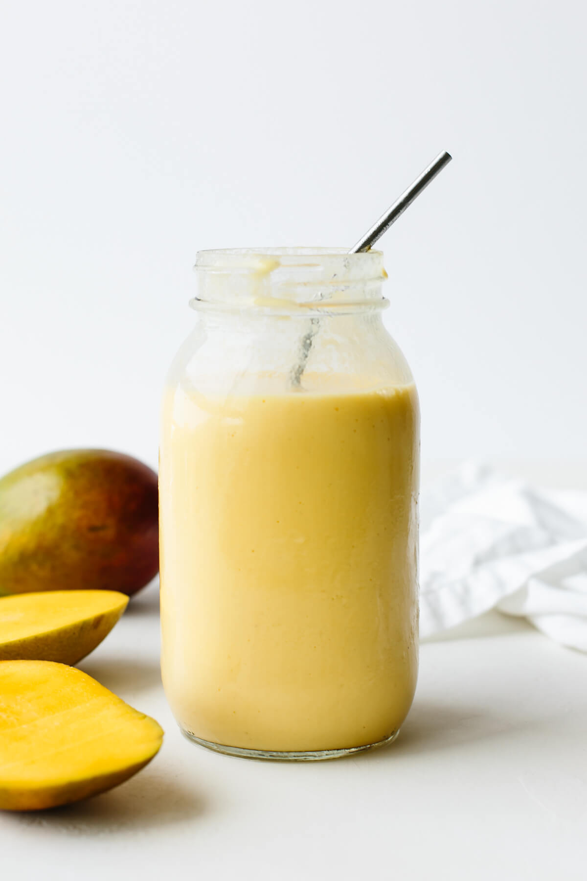 This creamy mango smoothie recipe is just the ultimate summer thirst quencher! mangos next to a mango smoothie