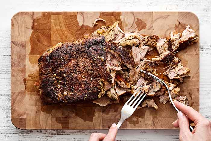Shredding pork on a board.