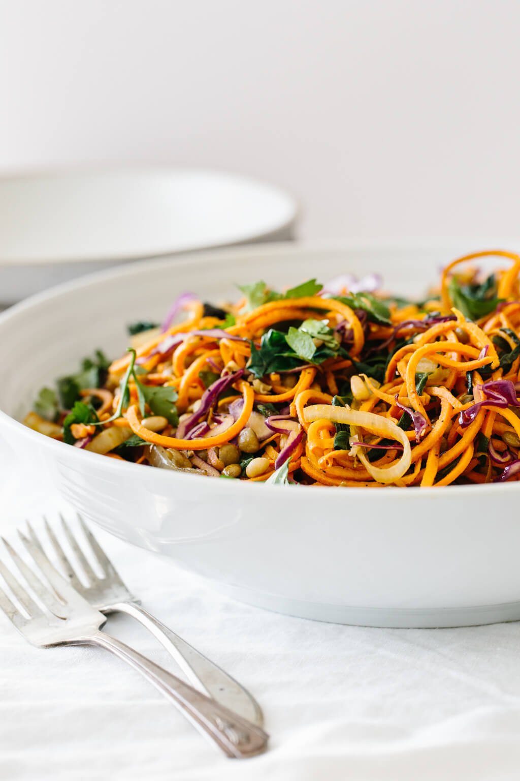 Sweet potato noodles salad is a combination of spiralized sweet potato noodles, cabbage, lentils, sautéed onions and Swiss chard. It's topped off with fresh herbs, toasted pine nuts and a zesty Dijon vinaigrette.