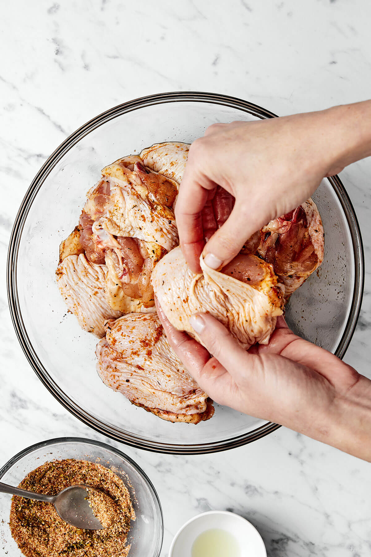These crispy and juicy baked chicken thighs make for the perfect weeknight meal. They’re incredibly easy to make and packed with flavor! Adding seasoning to chicken thighs.