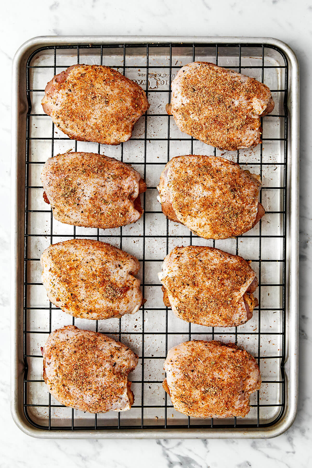 These crispy and juicy baked chicken thighs make for the perfect weeknight meal. They’re incredibly easy to make and packed with flavor! Chicken thighs on a baking sheet.