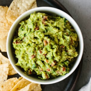 Guacamole in a bowl surrounded by chips.