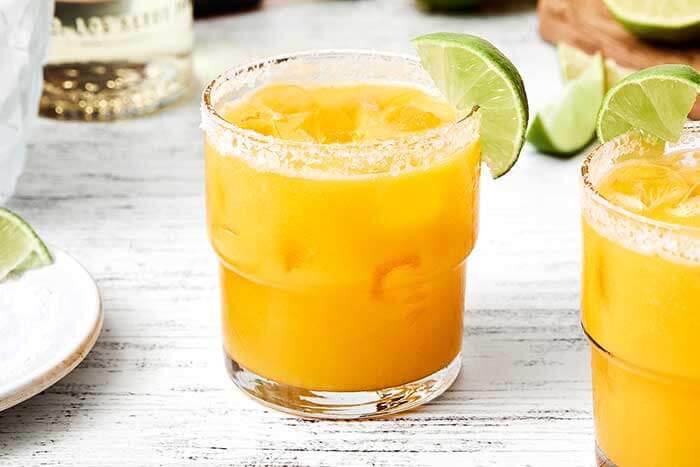 A mango margarita with a lime wedge.