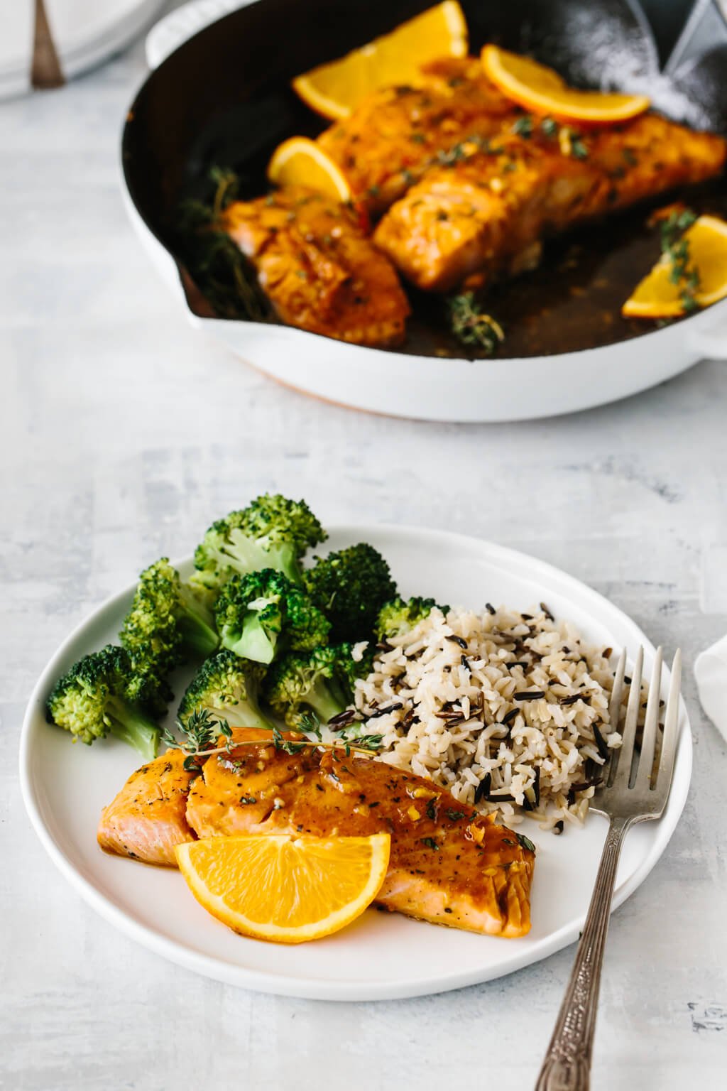 A white plate with salmon, rice and broccoli.