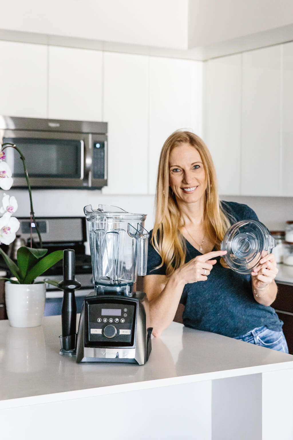 8 Vitamix tips, tricks and hacks you need to know! Girl standing next to Vitamix Blender pointing to the lid.