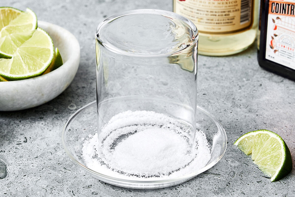 This classic margarita recipe is an easy cocktail with tequila, triple sec, and lime juice. Perfect for serving a crowd! Adding salt rim on a glass.