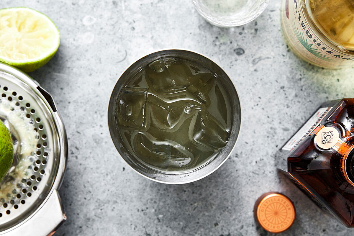 This classic margarita recipe is an easy cocktail with tequila, triple sec, and lime juice. Perfect for serving a crowd! Mixing margarita in a cup.