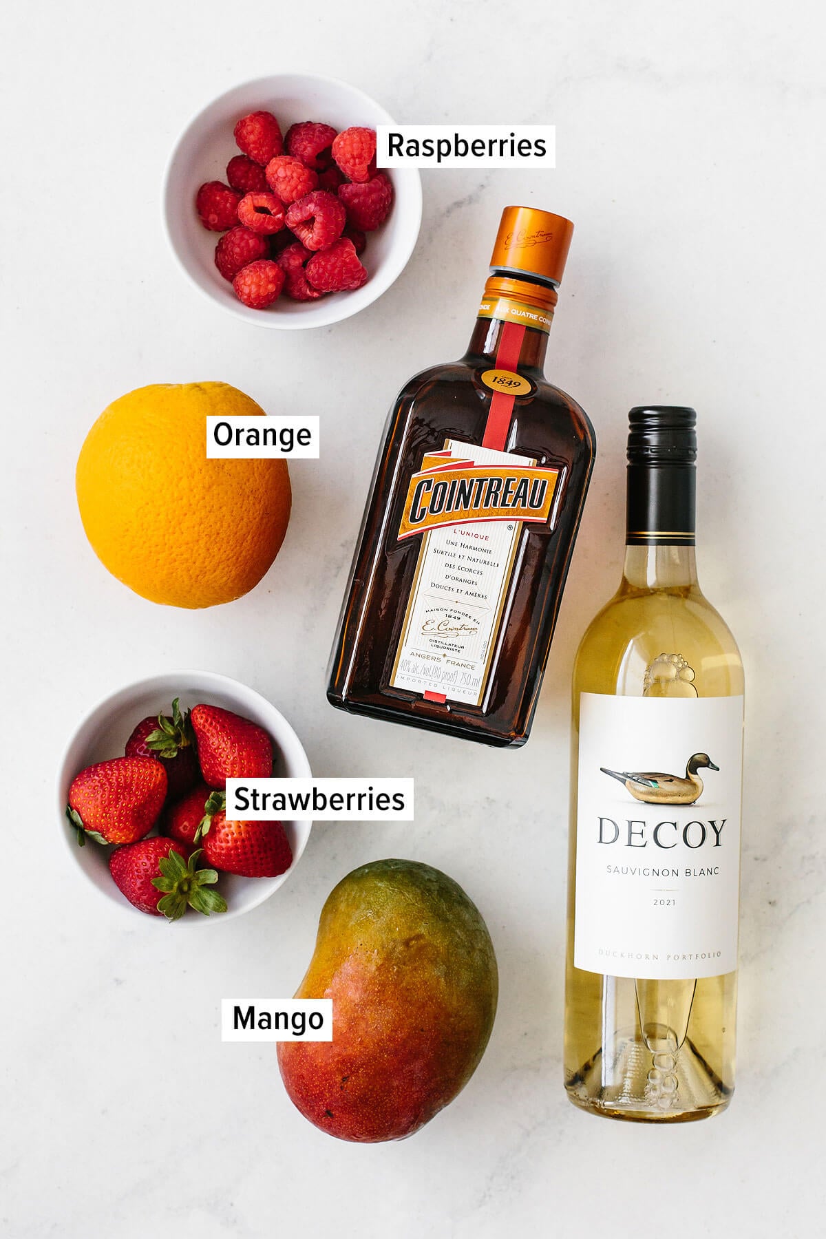 This white sangria with mango and berries is the perfect fruity, summer cocktail. Ingredients for white sangria on a table