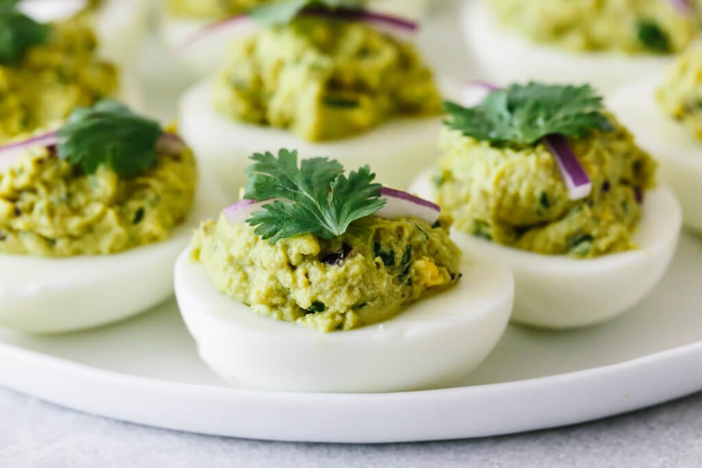 Avocado deviled eggs on a white plate.