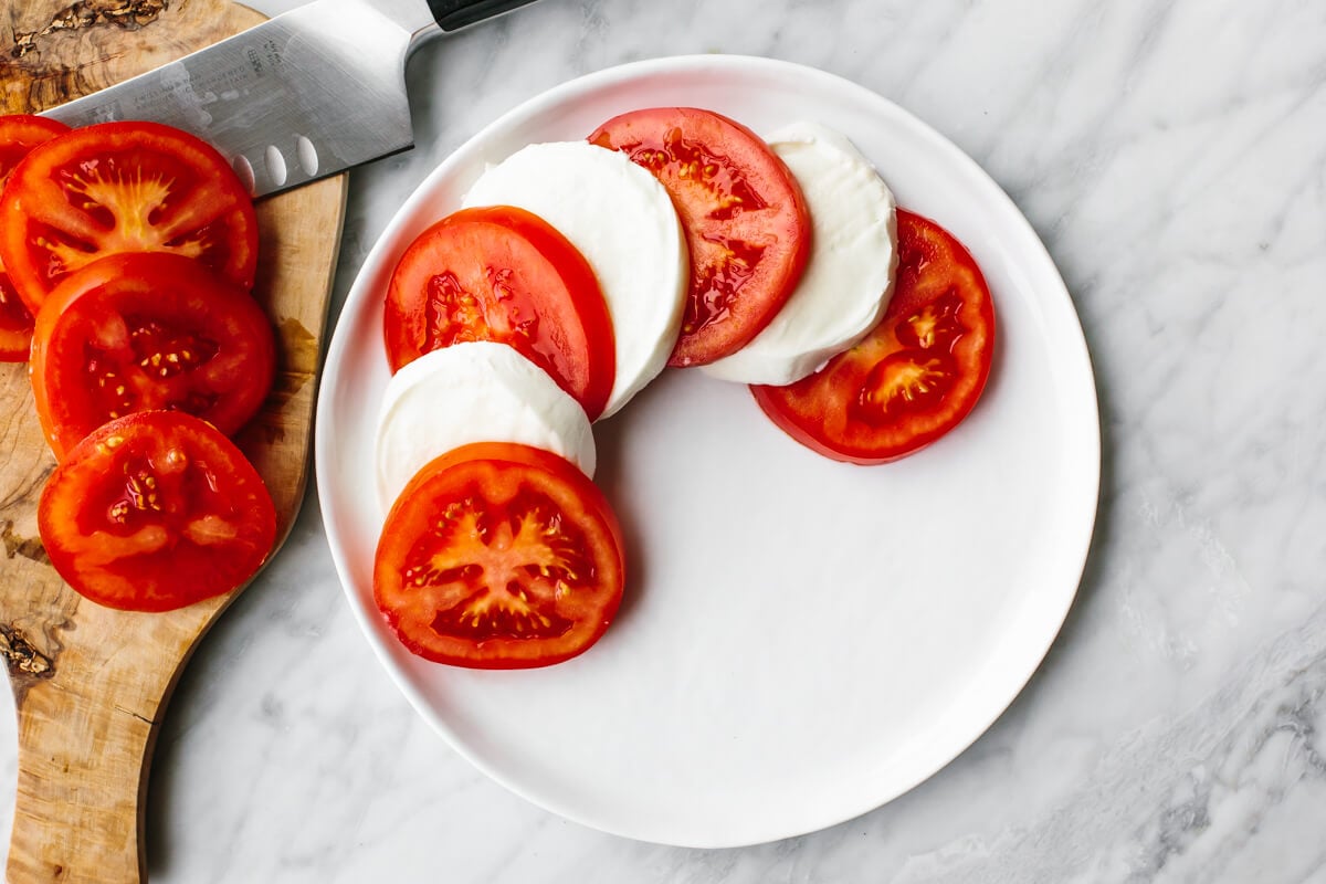 Caprese salad is a classic Italian salad with juicy tomatoes, mozzarella, basil leaves, and drizzled with olive oil and balsamic vinegar. Layering caprese salad on a plate