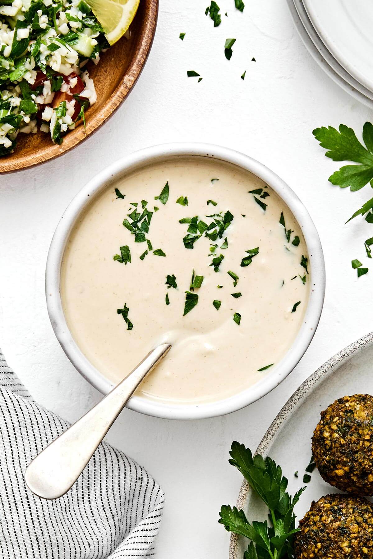 A bowl of tahini sauce with a spoon.
