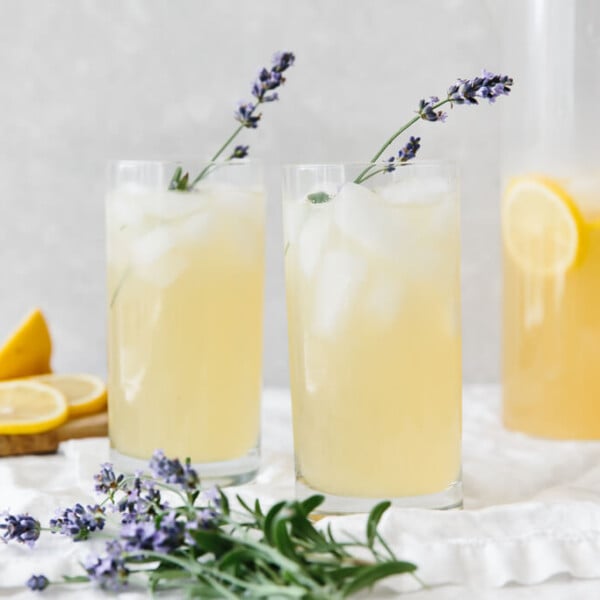 Two glasses of lavender lemonade on a table next to fresh lavender.