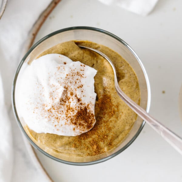 Pumpkin pie chia pudding mousse in a glass with a dollop of cream.