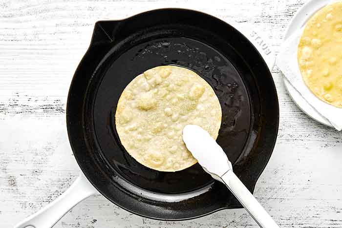 Frying a tortilla in a pan for huevos rancheros.