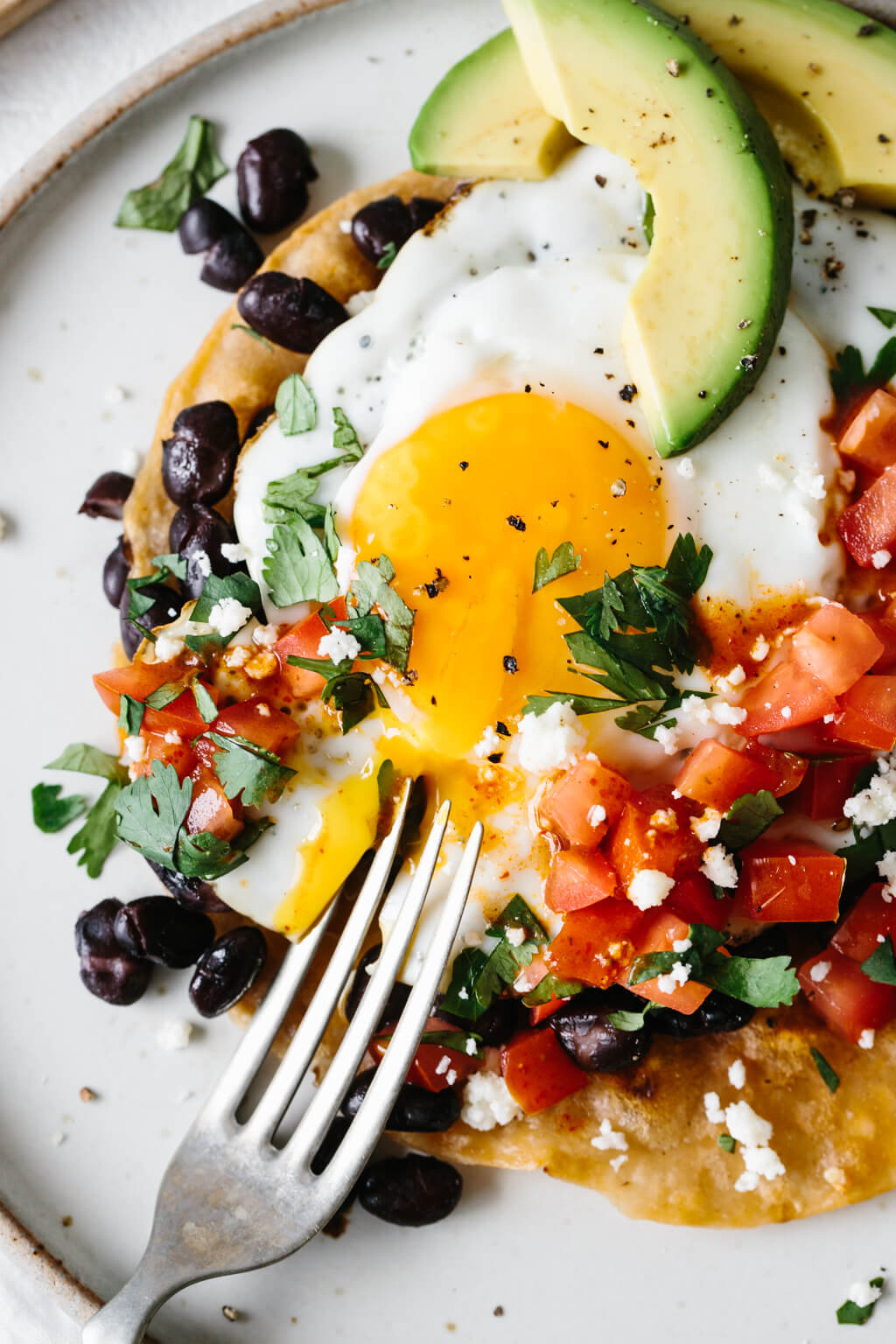 A fork broke open the yolk on a plate of huevos rancheros.