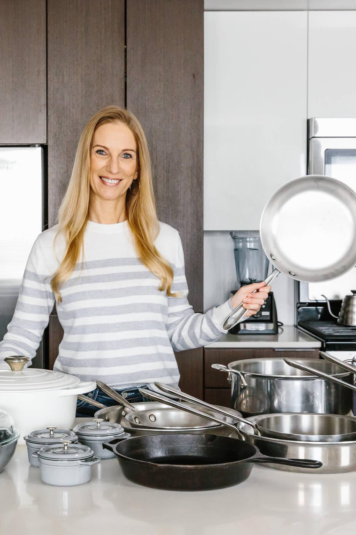 The best cookware worth the investment is durable, non-toxic and lasts a lifetime! The best cookware types all on a counter with girl holding stainless steel pan.