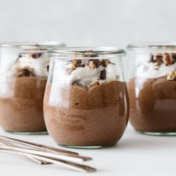 Three servings of chocolate chia pudding mousse with toppings.