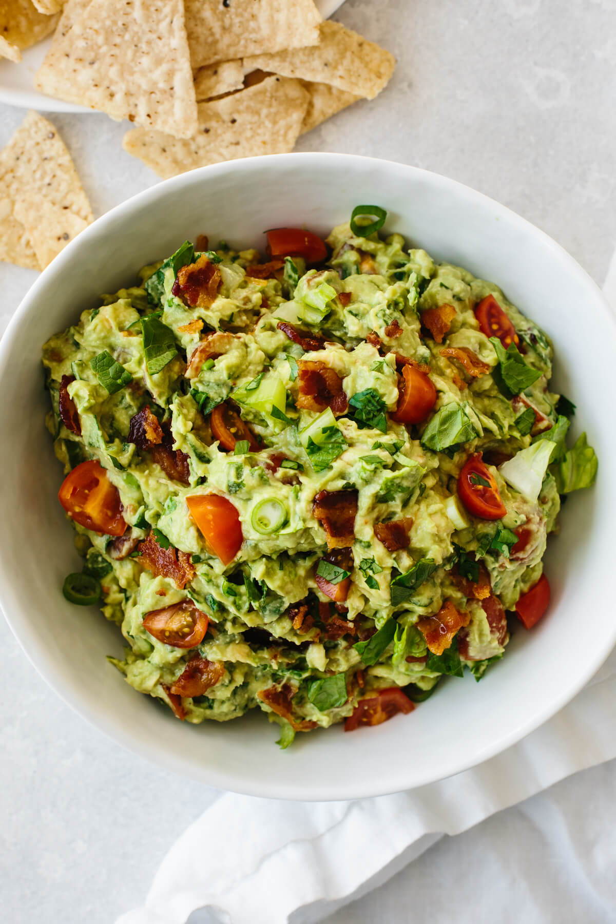 BLT guacamole in a white bowl next to chips.