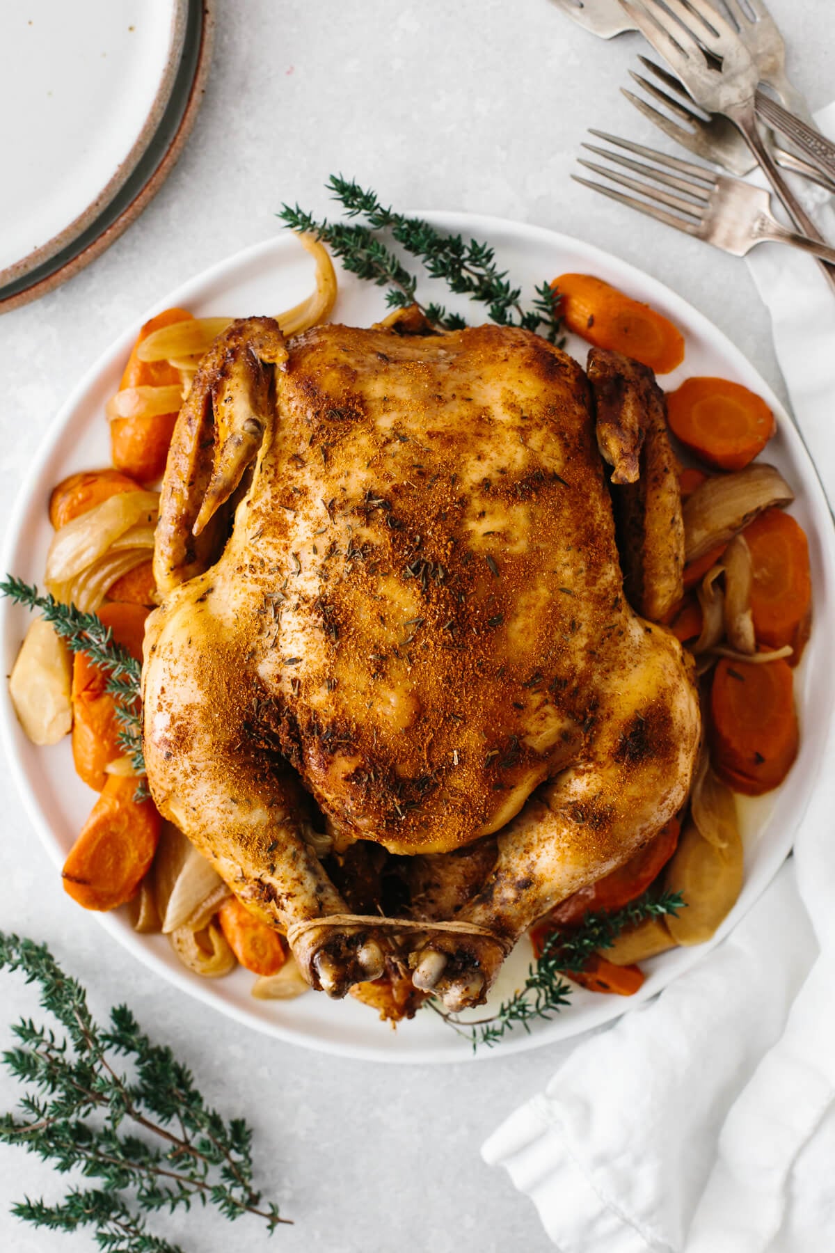 Slow cooker rotisserie chicken on a bed of vegetables on a plate.