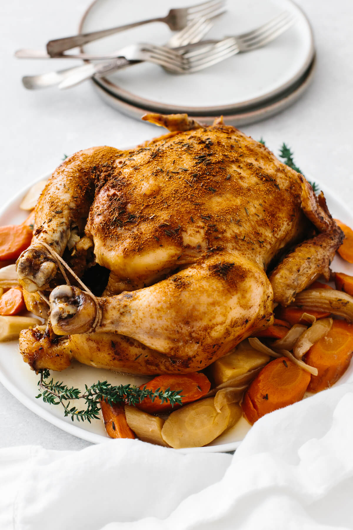 Slow cooker rotisserie chicken on a plate with vegetables.