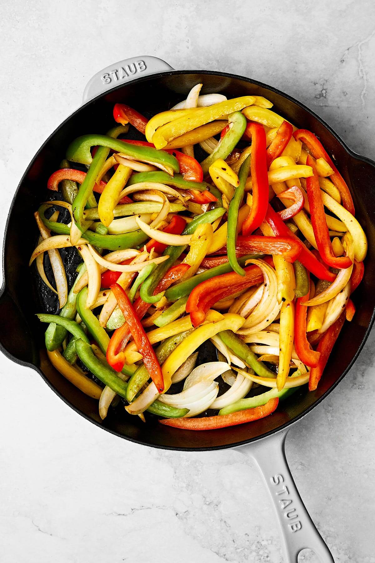 Enjoy these easy chicken fajitas with chicken and vibrant veggies tossed in the best fajita seasoning. Wrap them in tortillas for taco night! Cooking vegetables in a skillet.