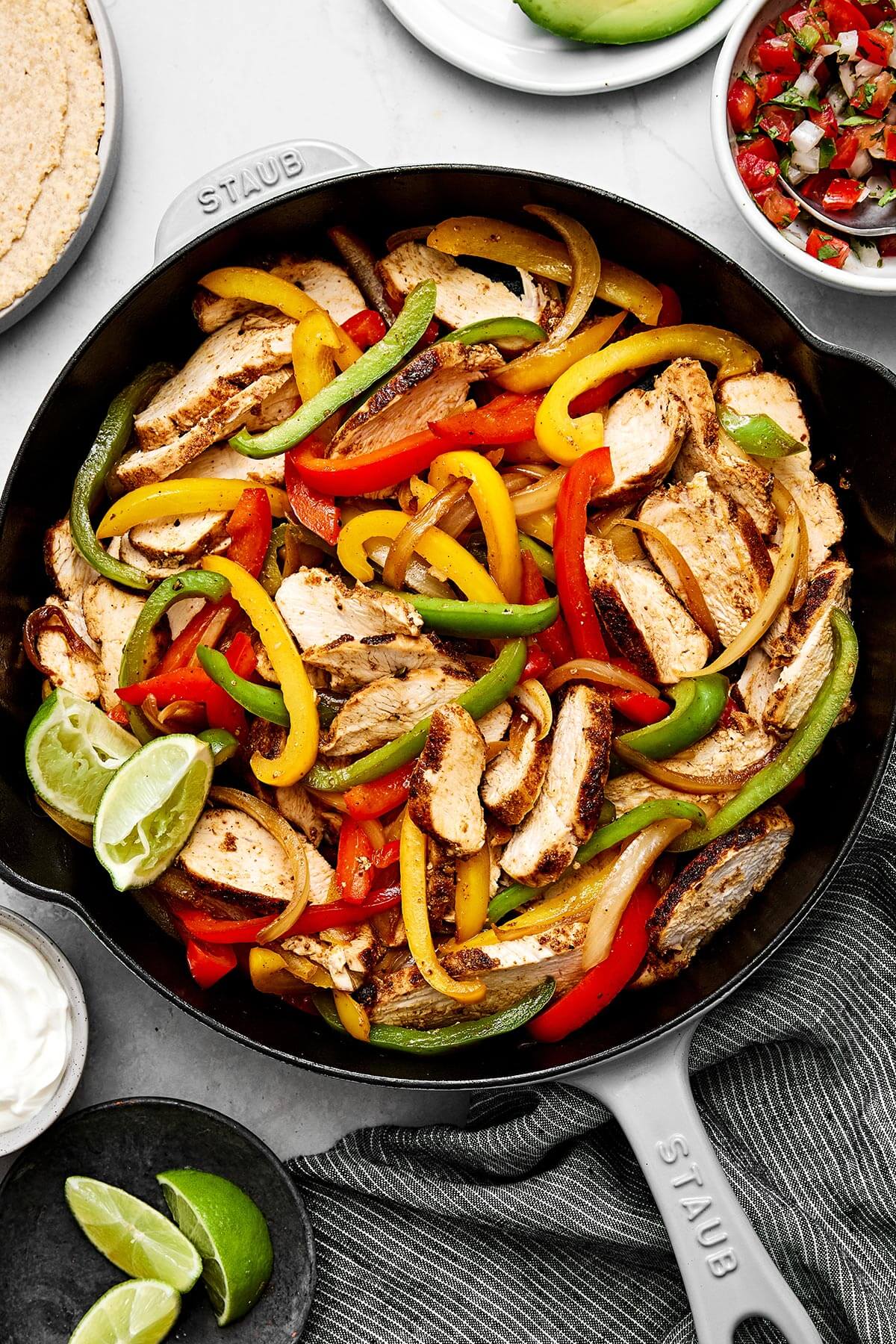 Enjoy these easy chicken fajitas with chicken and vibrant veggies tossed in the best fajita seasoning. Wrap them in tortillas for taco night! A skillet of chicken fajitas.
