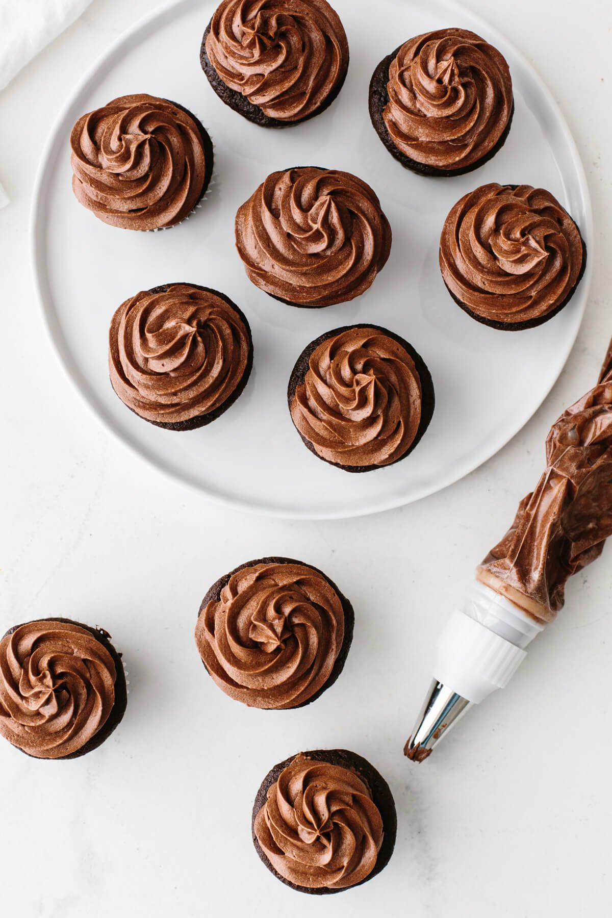 Piping the chocolate buttercream frosting on the cupcakes.