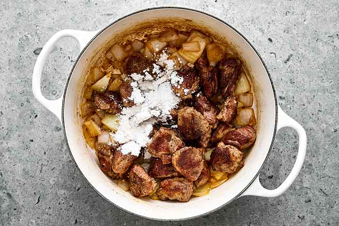 Step five of lamb stew: Add the flour.