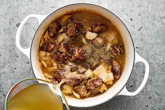 Step six of lamb stew: Add liquids and aromatics.