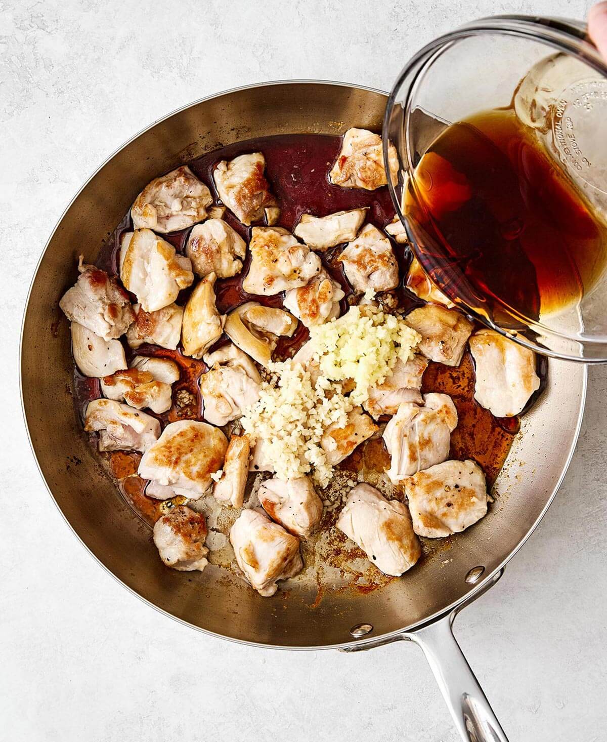 Cooking chicken thighs with teriyaki sauce.