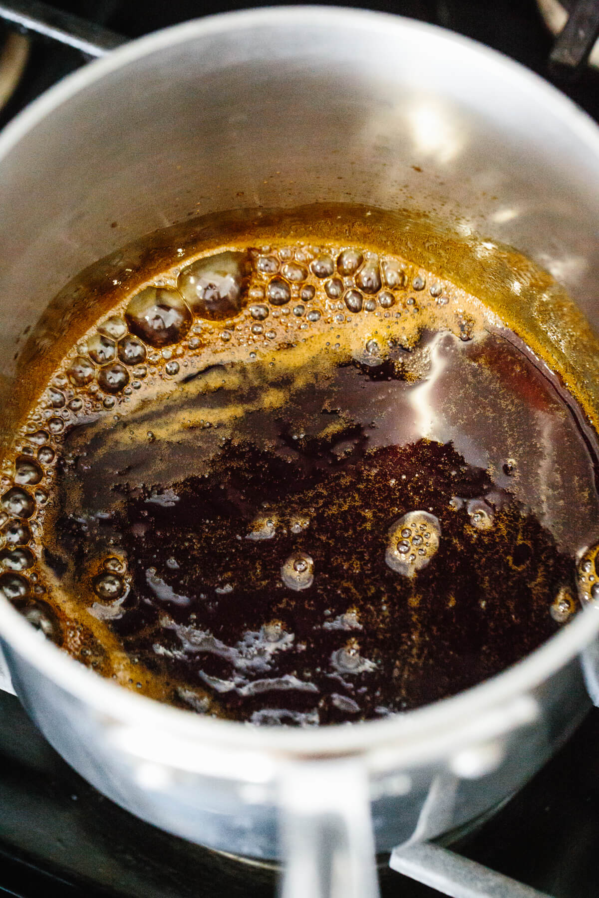 Reducing teriyaki sauce in a pot on the stove.