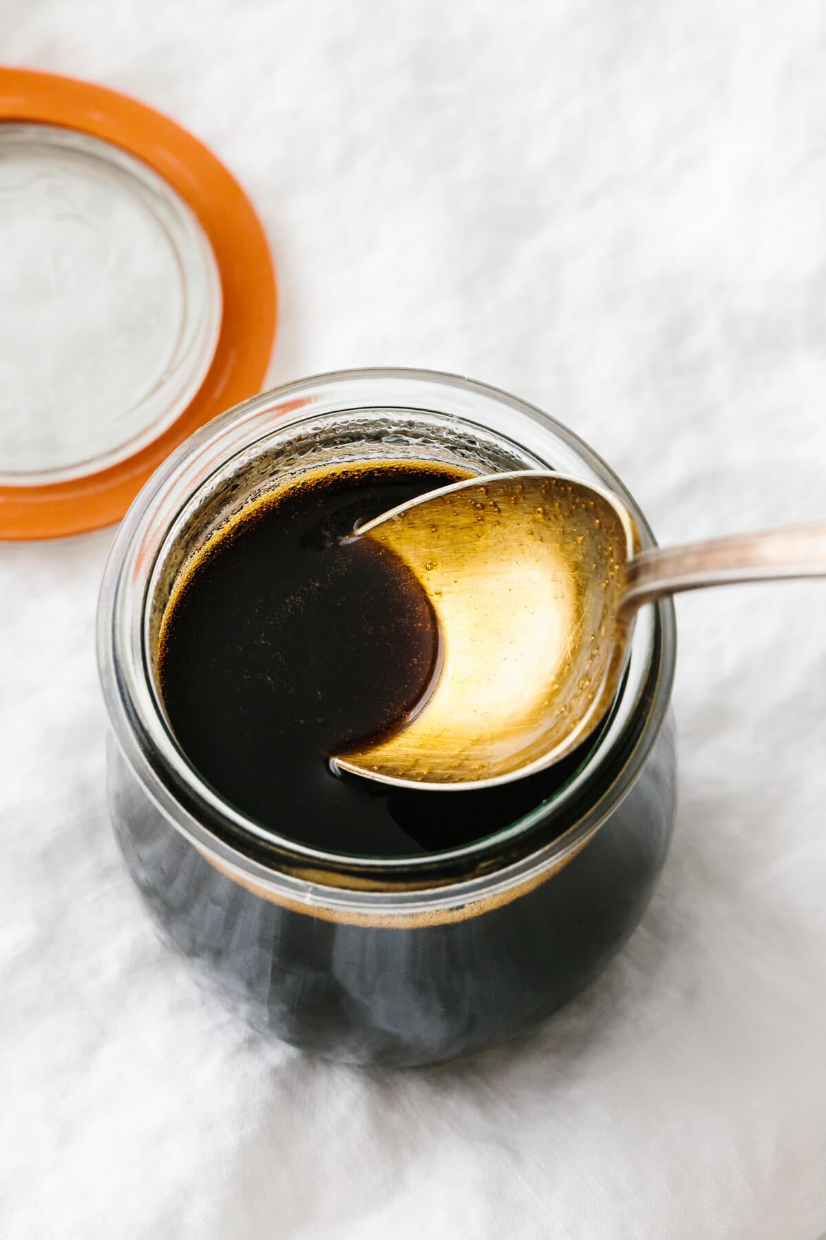 A spoon in a jar of teriyaki sauce.
