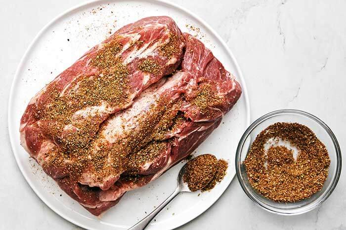 Adding seasoning on pork shoulder.